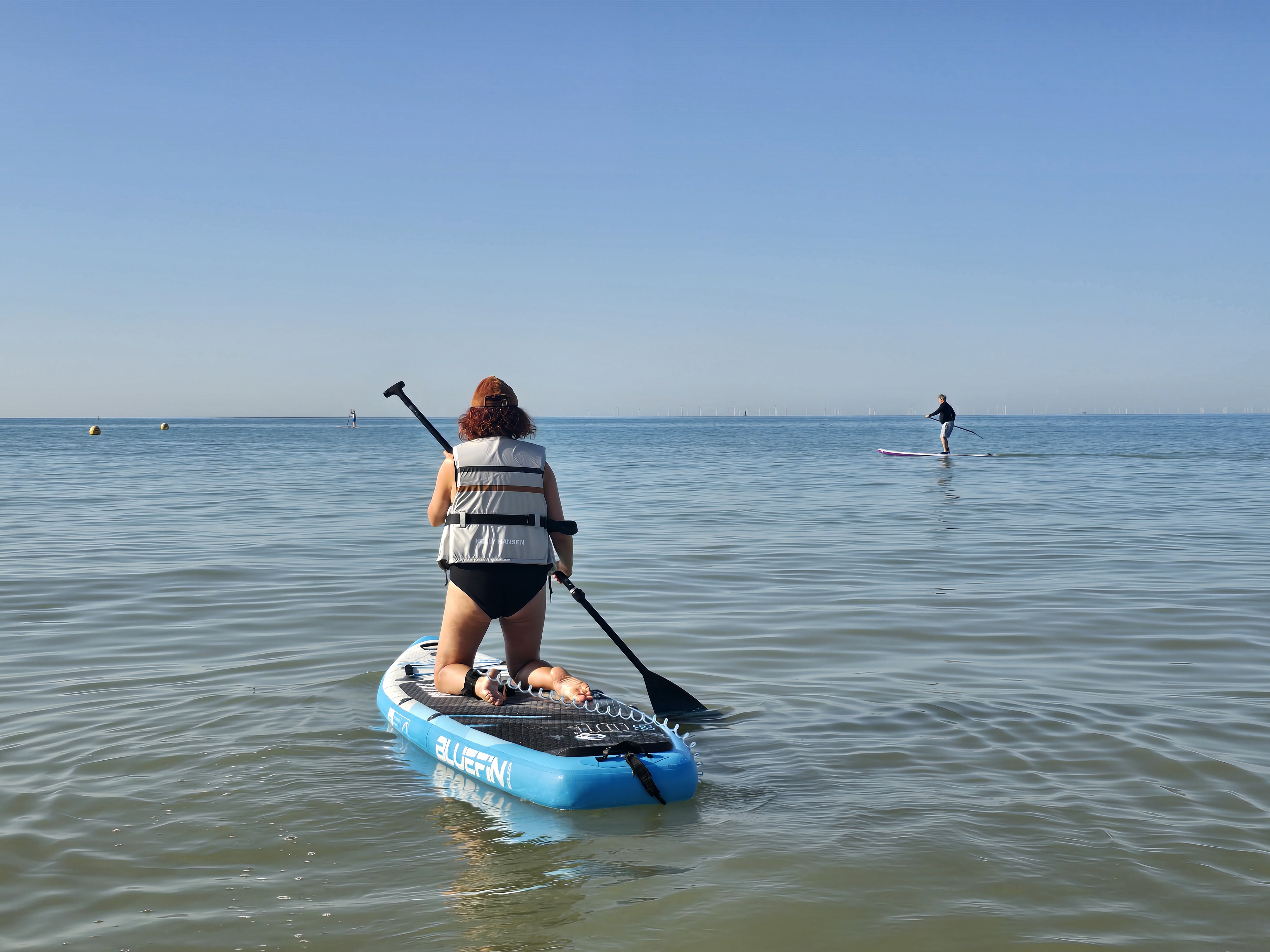 Paddleboarders on calm blue water near Brighton